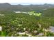 Breathtaking aerial view of homes nestled among mature trees, with a lake and golf course in the distance at 29962 Troutdale Ridge Rd, Evergreen, CO 80439