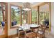 Bright dining area with floor-to-ceiling windows offering scenic forest views and access to a deck at 29962 Troutdale Ridge Rd, Evergreen, CO 80439