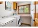 Functional laundry room with modern washer and dryer, ample counter space, and wooden shelving for storage at 29962 Troutdale Ridge Rd, Evergreen, CO 80439