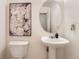 Elegant half bathroom with pedestal sink, decorative oval mirror, and stylish floral wall art at 1601 Great Western Dr # D3, Longmont, CO 80501