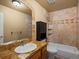 Bathroom featuring tan tile, a large mirror, and a tub with a tiled shower and built-in shelving at 5175 Quari St, Denver, CO 80239