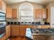 Close-up of kitchen with stainless steel cooktop, granite counters, and wood cabinets under a large arch window at 5175 Quari St, Denver, CO 80239