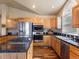 Bright kitchen featuring wooden cabinetry, granite countertops, stainless steel appliances, and a central cooktop island at 5175 Quari St, Denver, CO 80239