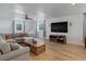 Spacious living room with cozy gray sofa, wood floors, media center, and natural light at 5175 Quari St, Denver, CO 80239