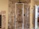 Beautiful glass enclosed shower with stone tile, a rainfall shower head, and built-in shelving at 5175 Quari St, Denver, CO 80239