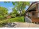 View of the green backyard with a mature tree, a wood fence, and a concrete patio leading to the house at 12771 W 6Th Pl, Lakewood, CO 80401