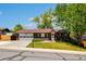 Charming brick home with attached two-car garage and well-manicured front lawn under a clear blue sky at 12771 W 6Th Pl, Lakewood, CO 80401