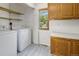 Well-lit laundry room with modern washer and dryer, wood cabinets, and a bright window at 12771 W 6Th Pl, Lakewood, CO 80401
