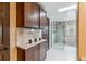 Well-lit bathroom with a glass shower, a skylight, and decorative dark cabinets at 40192 Margaret Dr, Elizabeth, CO 80107