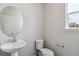 Half bath featuring a pedestal sink, oval mirror, toilet, and bright natural light at 14145 Deertrack Ln, Parker, CO 80134