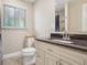 Elegant bathroom featuring granite countertops, wood cabinets, and a window with natural light at 7650 W 24Th Ave, Lakewood, CO 80214