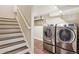Laundry area featuring modern washer and dryer units, tile floors, and a staircase nearby at 7650 W 24Th Ave, Lakewood, CO 80214