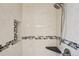 Close-up of the shower with mosaic tile accents, handheld shower head and a corner shelf at 7650 W 24Th Ave, Lakewood, CO 80214