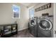 Convenient laundry room featuring modern washer and dryer, shelving, and bright natural light from two windows at 1867 W 137Th Ln, Broomfield, CO 80023