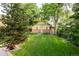 Well-manicured backyard featuring green lawn, mature trees, and a charming outbuilding at 4224 N Clay St, Denver, CO 80211
