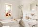 Bright bathroom with a clawfoot tub, pedestal sink, and stained glass window at 4224 N Clay St, Denver, CO 80211