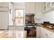 Kitchen with stainless steel appliances, granite countertops, decorative window, and white cabinetry at 4224 N Clay St, Denver, CO 80211