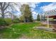 Lush backyard with mature trees, green lawn, beautiful landscaping and a charming pergola covered deck at 9391 W Hialeah Pl, Littleton, CO 80123