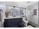 Modern bathroom featuring a navy blue vanity, round mirror, and glass-enclosed shower with custom tile work at 9391 W Hialeah Pl, Littleton, CO 80123