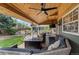Inviting covered outdoor living area with comfortable seating, ceiling fan, and outdoor TV for entertainment at 9391 W Hialeah Pl, Littleton, CO 80123