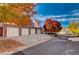 Exterior view of townhomes with multiple garages and brick accents, set on a tree-lined street in autumn at 10380 W 55Th Ln # 204, Arvada, CO 80002