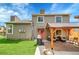 Back exterior of home featuring a covered patio, seating, and a well-manicured lawn at 12433 Bellaire Dr, Thornton, CO 80241