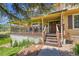 Inviting covered front porch with wood railing and stairs and manicured landscaping at 25741 E Kettle Cir, Aurora, CO 80016
