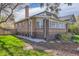A brick home featuring a sunroom with large windows, a well-maintained lawn, and mature trees at 1230 S Emerson St Dr, Denver, CO 80210