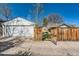 A detached two-car garage with a white exterior, wooden gate entrance, and a concrete driveway at 1230 S Emerson St Dr, Denver, CO 80210