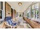 Spacious, light-filled porch with brick accents, slate flooring, comfortable seating, and open windows at 1230 S Emerson St Dr, Denver, CO 80210