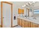 This bathroom features a dual sink vanity with oak cabinets and granite counters at 6279 Cheyenne Ct, Parker, CO 80134