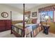Cozy bedroom featuring a four-poster bed, dresser, and windows with valances overlooking the outdoors at 6279 Cheyenne Ct, Parker, CO 80134
