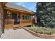 Inviting front porch with brick accents, a wooden railing, and charming landscaping at 6279 Cheyenne Ct, Parker, CO 80134