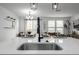 Modern kitchen island has quartz countertops and black hardware fixtures, with the dining area in background at 13860 Ash Cir, Thornton, CO 80602