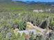 Expansive aerial shot of a secluded house nestled among lush green forests and distant mountain ranges at 8340 London Ln, Conifer, CO 80433