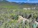 Expansive aerial shot of a secluded house nestled among lush green forests and distant mountain ranges at 8340 London Ln, Conifer, CO 80433