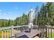 Outdoor deck featuring a table with an umbrella, surrounded by lush greenery and serene mountain views at 8340 London Ln, Conifer, CO 80433