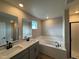 Modern bathroom featuring double vanity sinks, soaking tub with subway tile, and walk-in shower at 9353 Yampa Ct, Commerce City, CO 80022