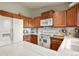 Efficient kitchen with white tile countertops, wooden cabinets, and essential appliances for everyday cooking at 34101 Columbine E Trl, Elizabeth, CO 80107