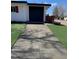Well-maintained concrete driveway leading to a home with a black garage door and manicured lawn at 6511 S Cedar St, Littleton, CO 80120