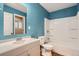 Bathroom with a white vanity, modern fixtures, a bathtub and a blue accent wall at 921 Dakin St, Denver, CO 80221