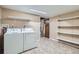 Laundry room with washer, dryer, tile floor, storage shelving, and utility sink at 921 Dakin St, Denver, CO 80221