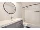 Bathroom featuring a tub with shower, single sink vanity and modern updates, and a round mirror at 4960 E Donald Ave # 11, Denver, CO 80222