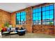 Living room showcases exposed brick walls, large windows, and a modern black leather sofa for comfortable lounging at 2500 Walnut St # 102, Denver, CO 80205