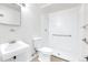 An all-white bathroom featuring a tiled shower with grab bar, toilet, and a simple sink at 8030 Ogden St, Denver, CO 80229
