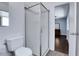 Bathroom with white toilet, frameless glass shower doors leading to bedroom with hardwood floors at 8030 Ogden St, Denver, CO 80229