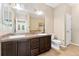 Bathroom featuring double sinks, dark cabinets, tiled floors, and a separate toilet area at 9637 E 5Th Ave # 101, Denver, CO 80230