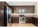Well-lit kitchen featuring stainless steel appliances, dark cabinetry, and tile flooring at 9637 E 5Th Ave # 101, Denver, CO 80230