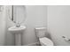Clean half-bathroom with white toilet, sink, and modern fixtures at 45940 Gentry Ave, Bennett, CO 80102