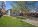 Grassy backyard with a large tree, privacy fence, and patio area with stone tiles at 3042 N Franklin St, Denver, CO 80205